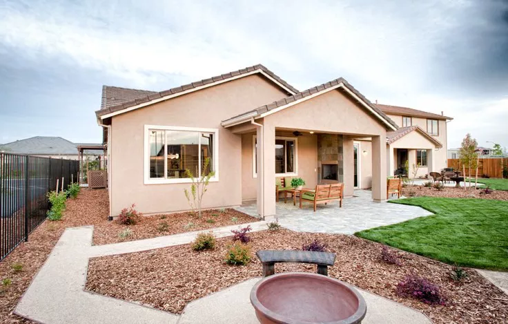 Natural landscaping in front of a tan home by Premier Homes.