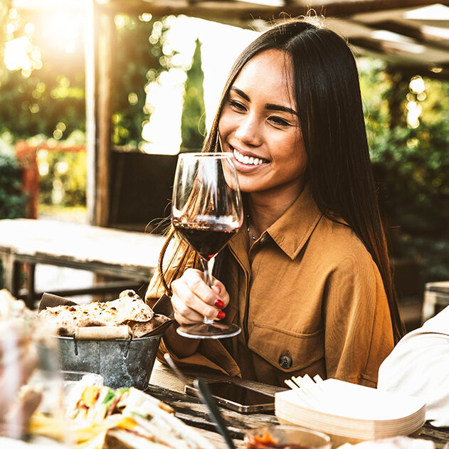 Happy asian woman drinking red wine sitting at restaurant dining